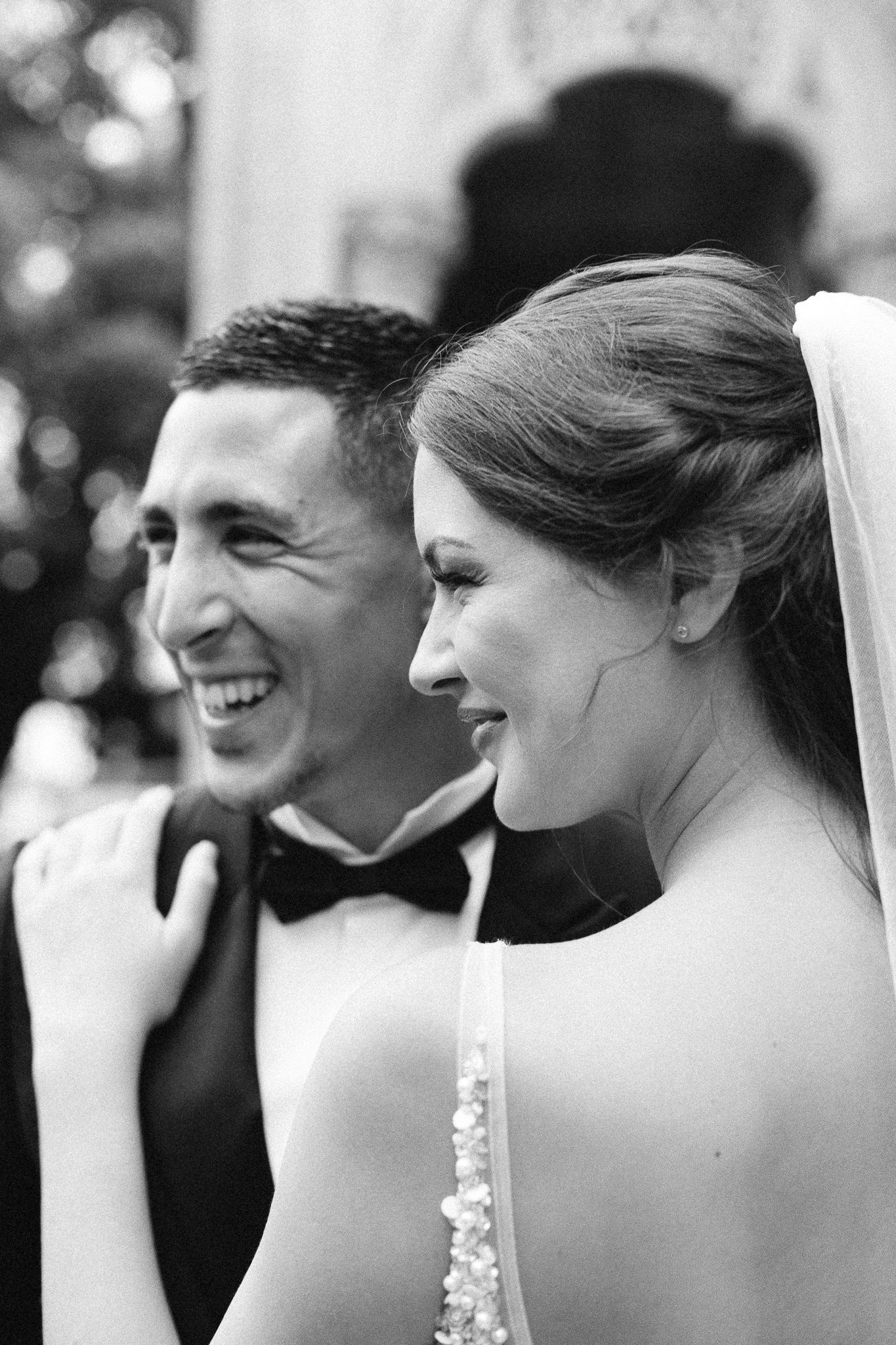 A black and white portrait of a happy bride and groom smiling together on their wedding day.