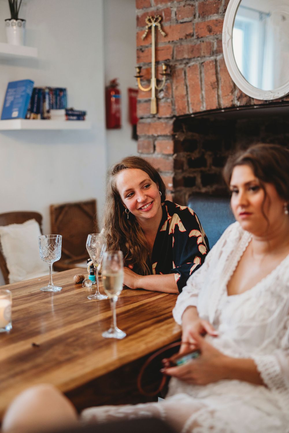 Friends enjoying drinks and conversation at a rustic wooden table with exposed brick walls.