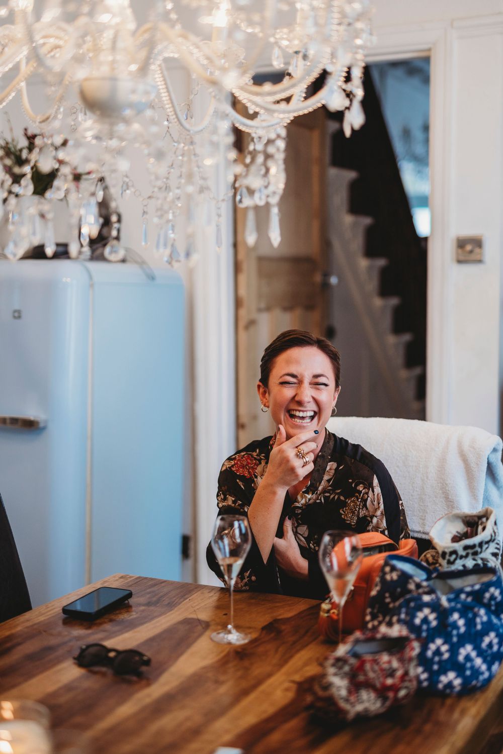 A candid moment of joy captured under a crystal chandelier at a wedding celebration.