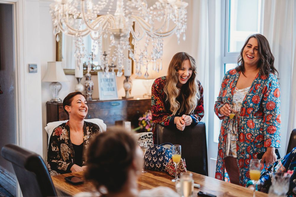 Wedding party gathering in a bright room with chandelier and elegant decor.