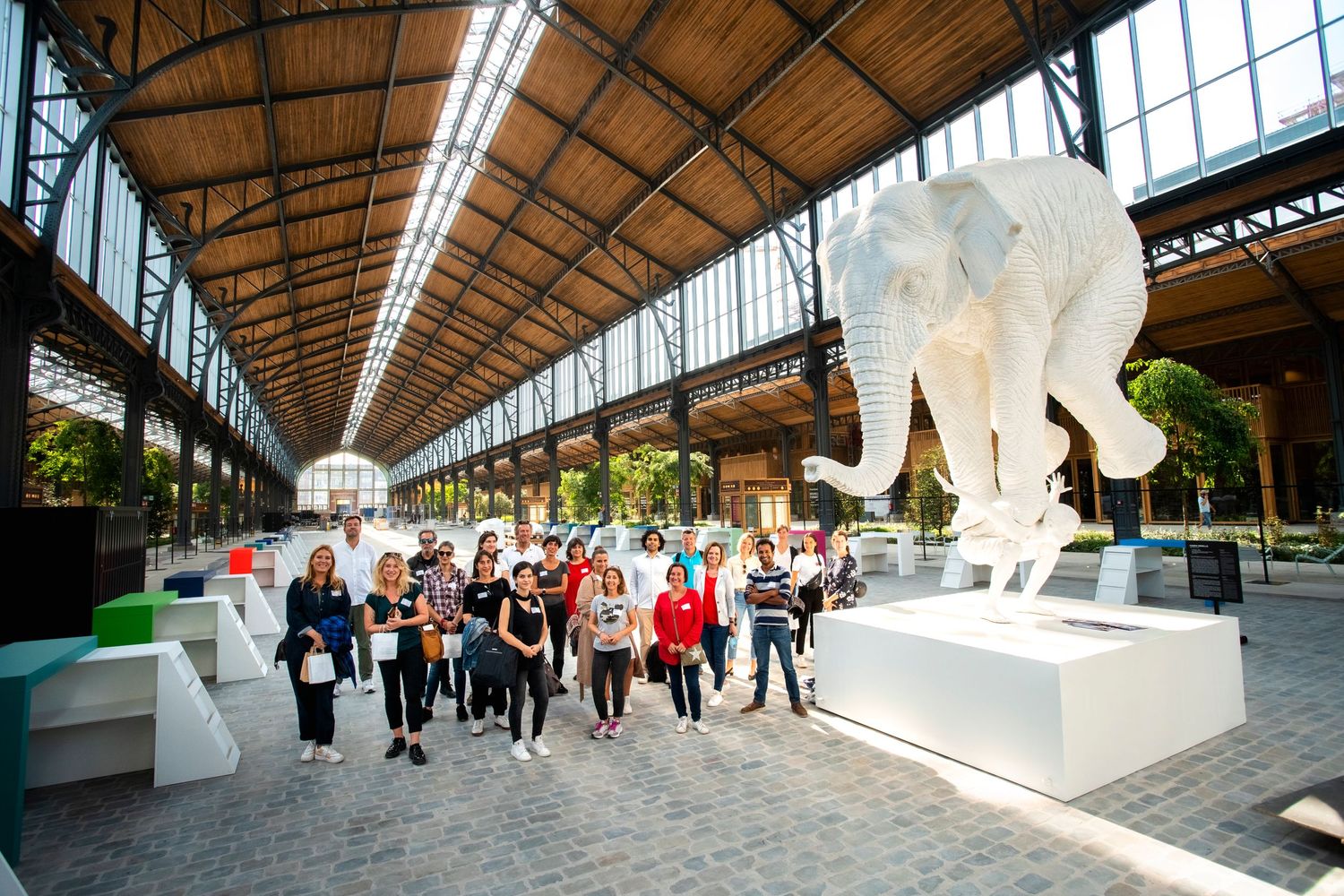 People walking through an indoor exhibition space with a large white elephant sculpture.