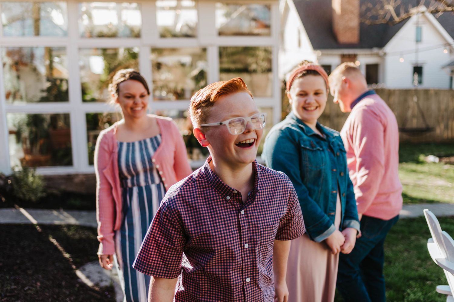 a family poses outside of a greenhouse during a family photo session