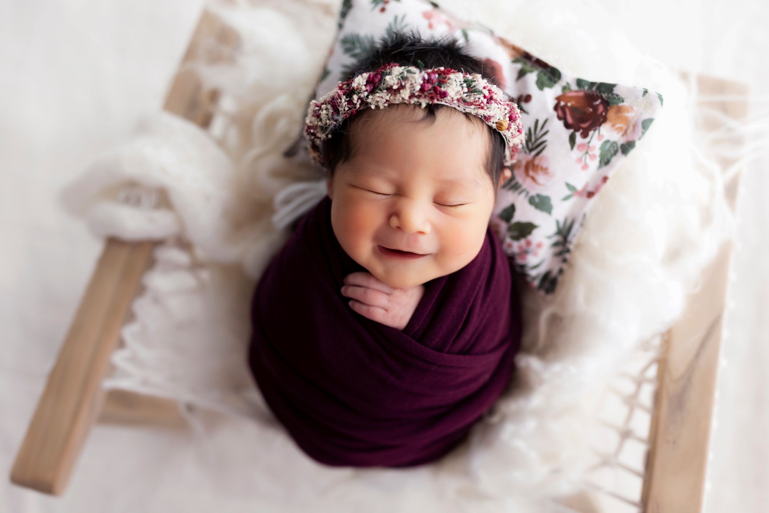 Newborn photography series featuring sleeping baby in purple wrap with floral accessories.