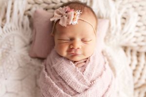 Artistic newborn portrait series with baby wrapped in soft pink fabric.