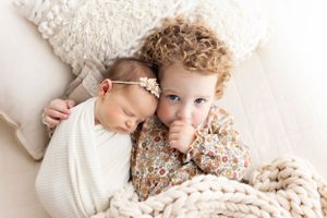 Intimate family photography session with soft cream colored textiles and natural lighting.