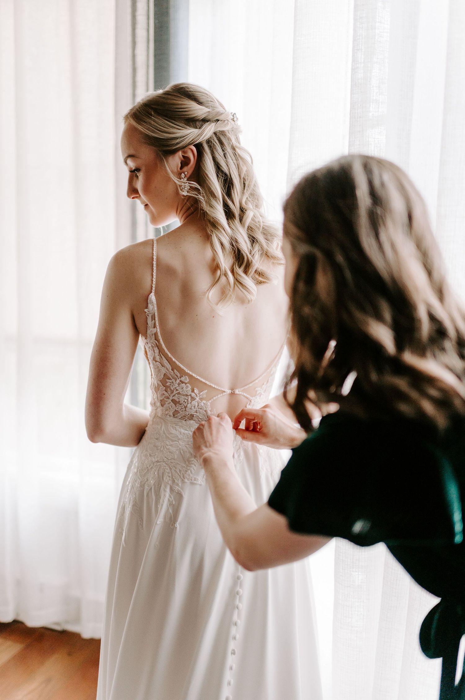 Close up of white lace wedding dress being adjusted.