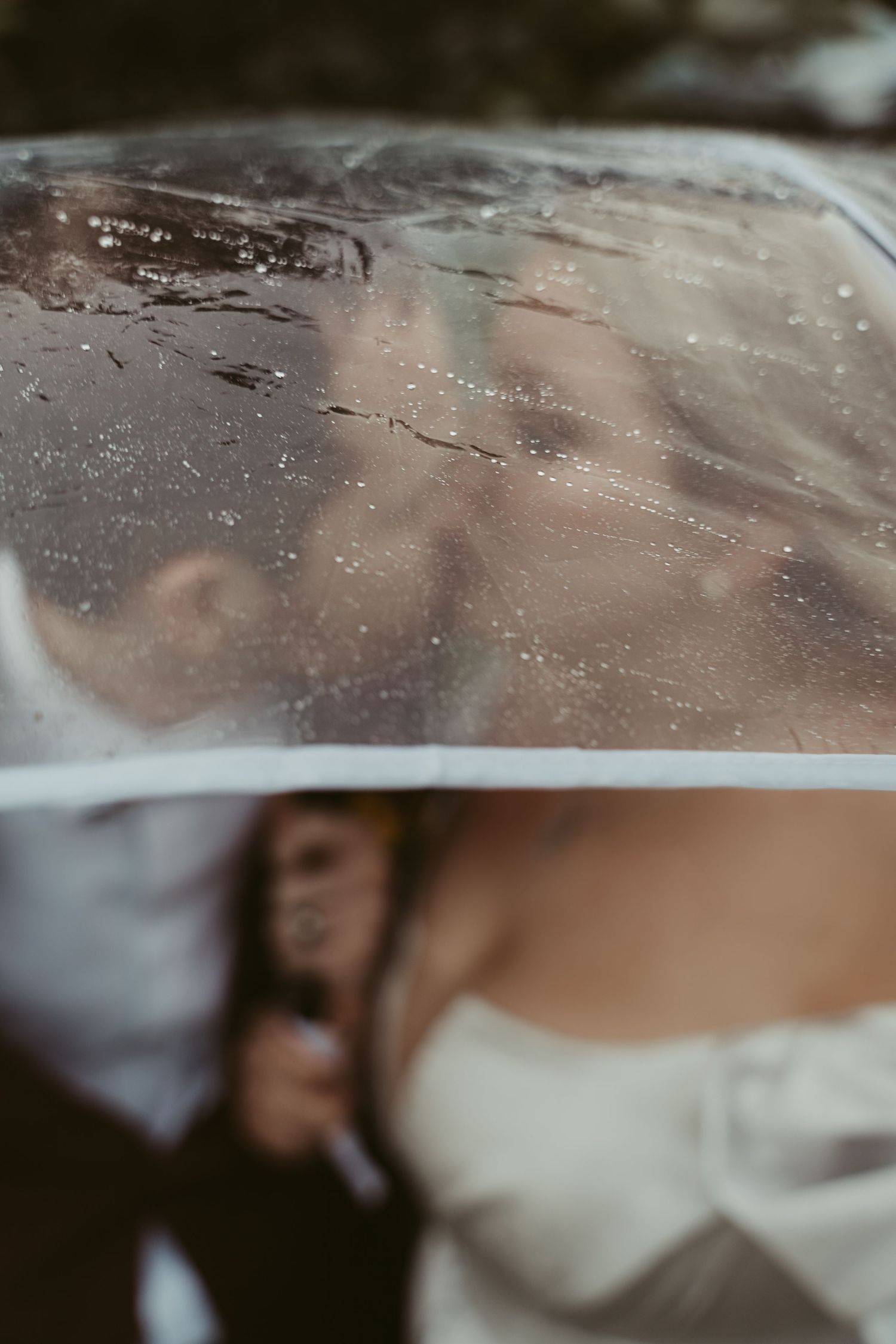 Artistic wedding photo reflection through rain-covered glass.