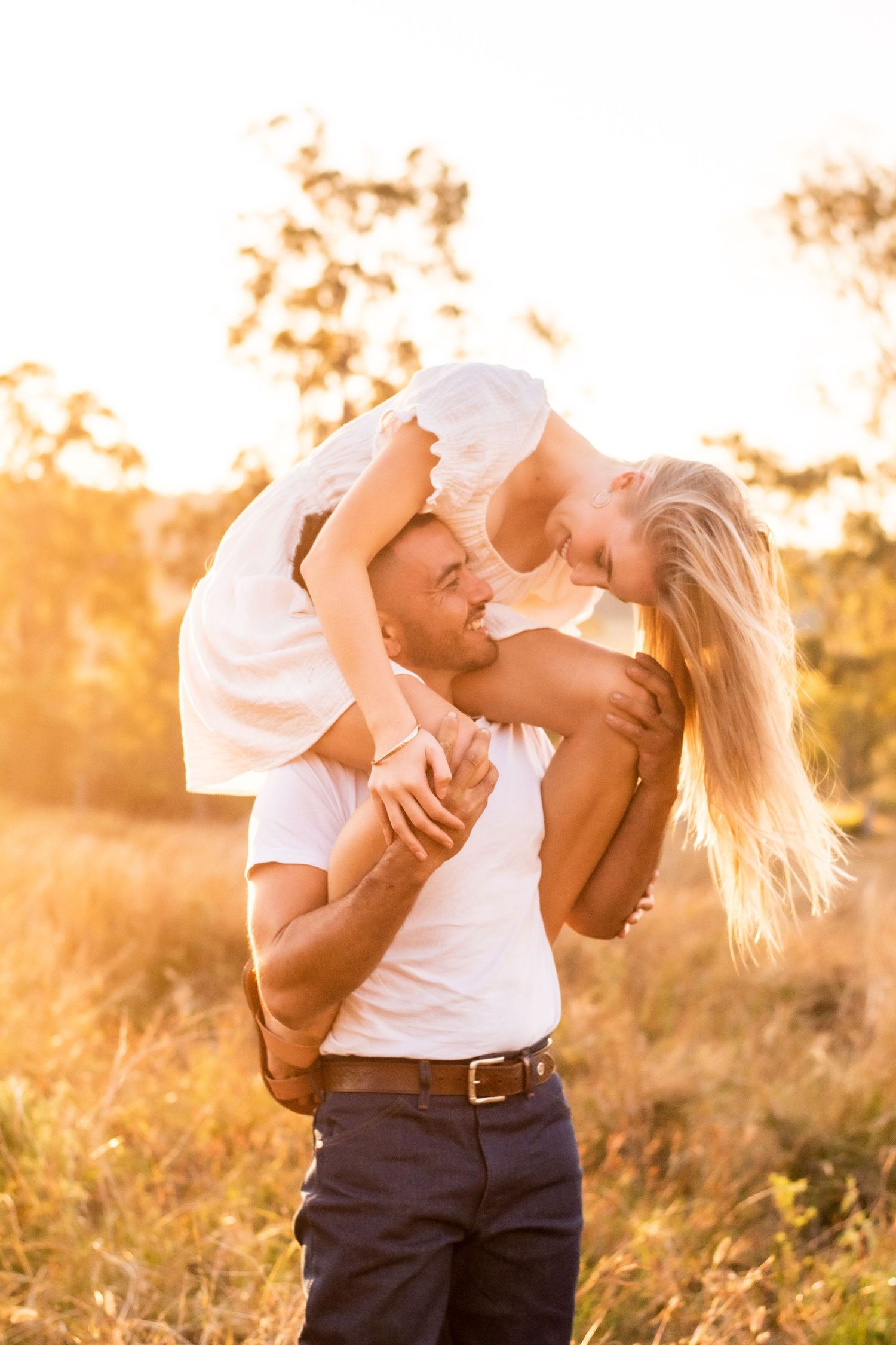 Intimate couple photo session in a sunlit field during sunset.