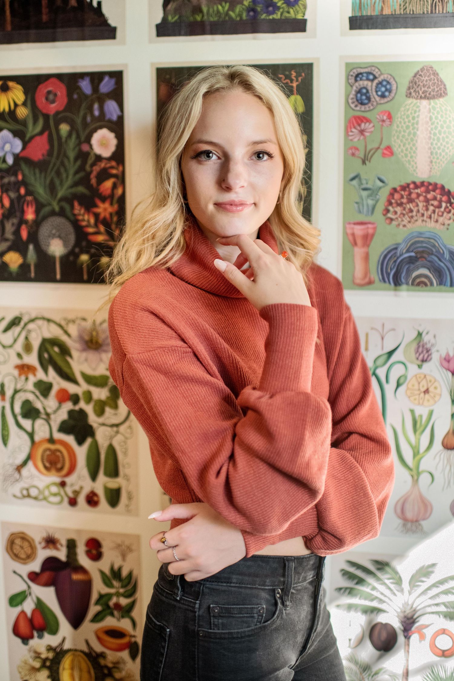 Portrait in a peach sweater against a colorful floral mural background.