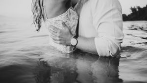 A romantic black and white photo of a couple in water.