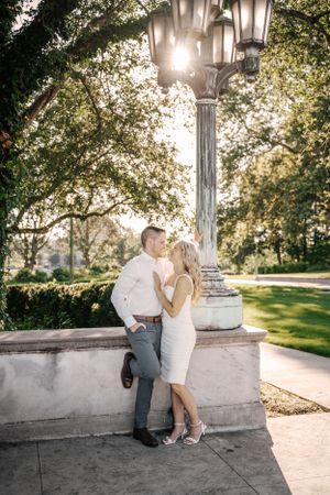 A romantic moment between a couple by a vintage lamppost in a manicured garden.