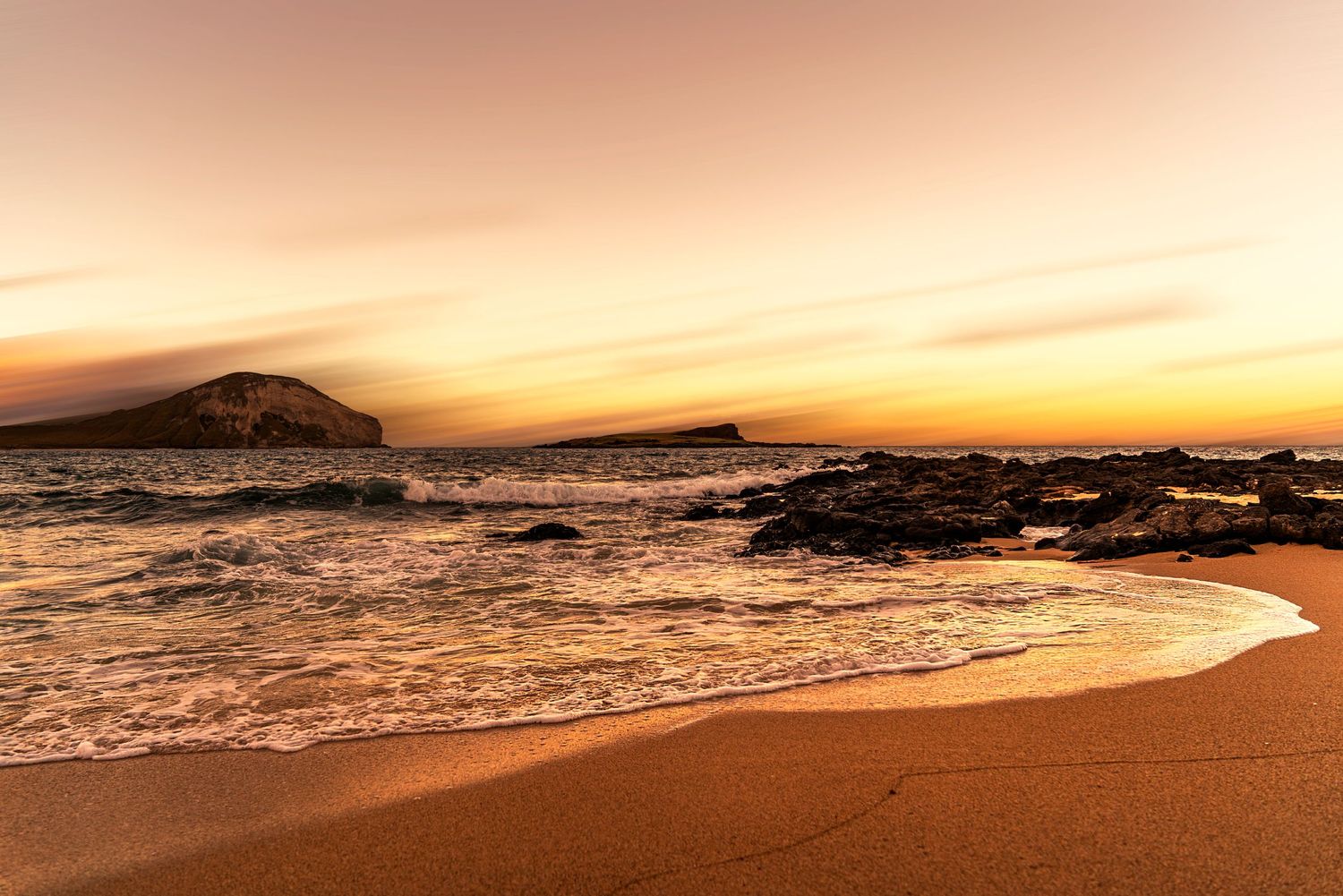 Golden sunset over rocky Hawaiian coastline with waves crashing on sandy beach. Fine Art Photography