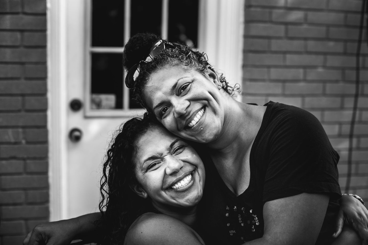Two sisters hug one another as they look at the camera.