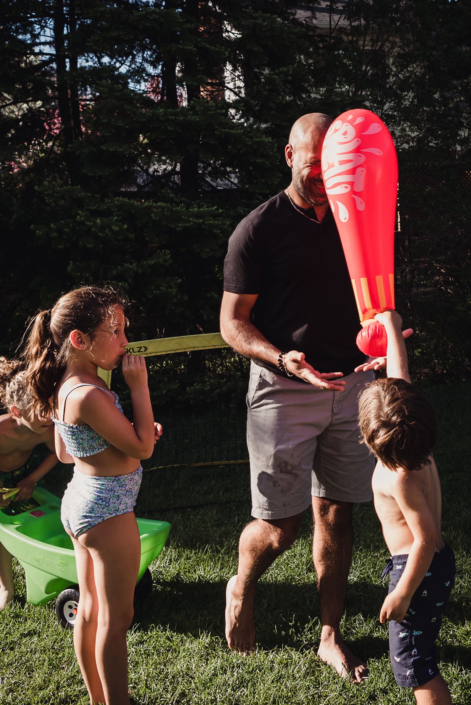 A child bonks an adult with a blow up red bat.