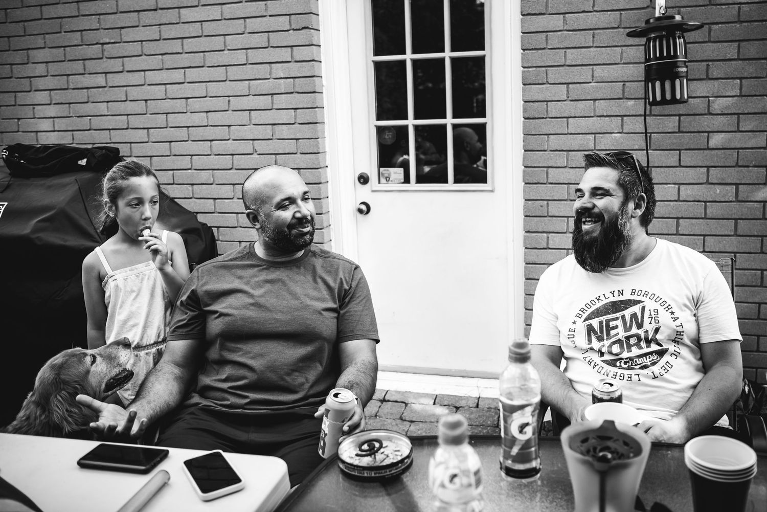 Two men sit apart at a table and smile as they talk.