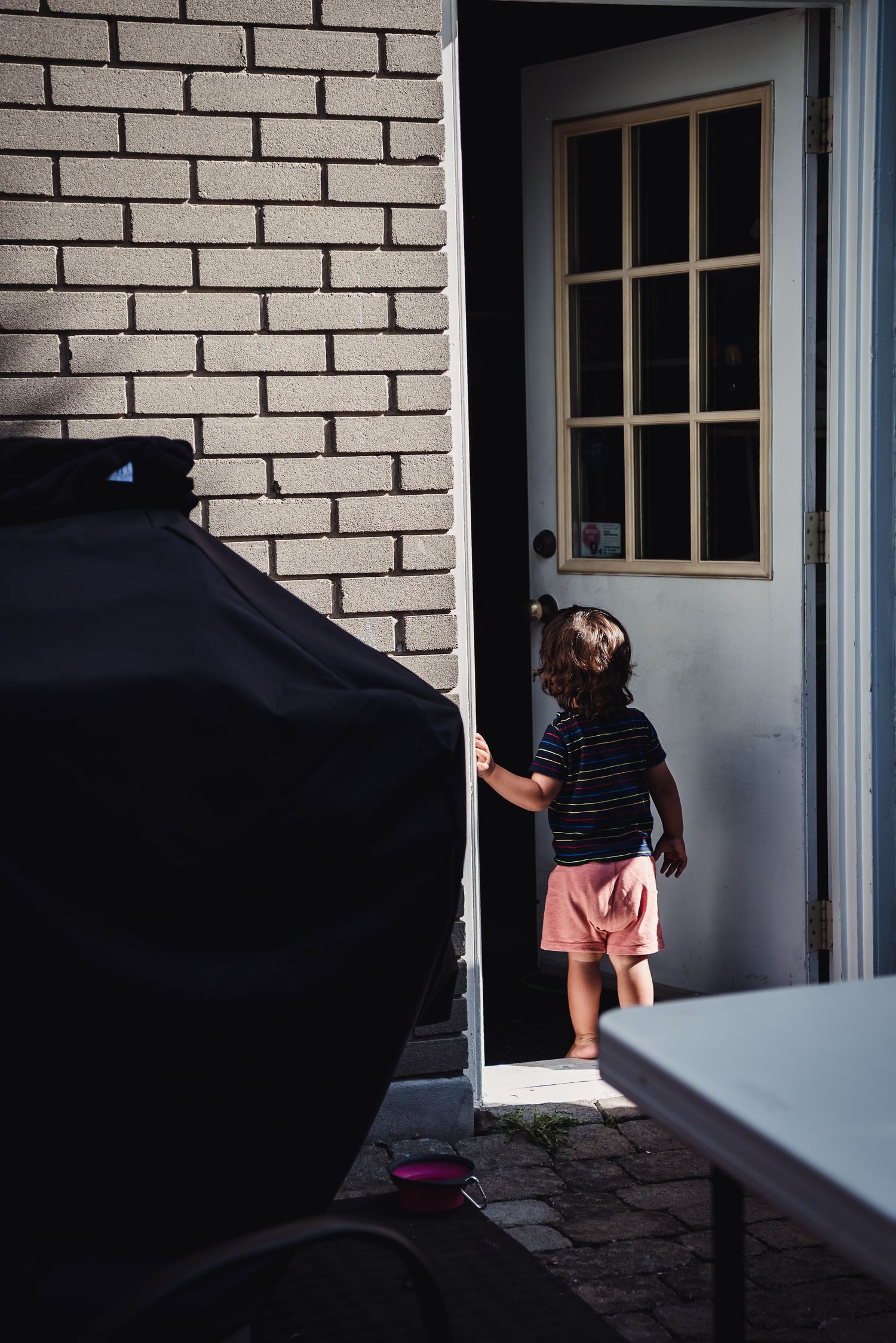 A little boy peers into a door.