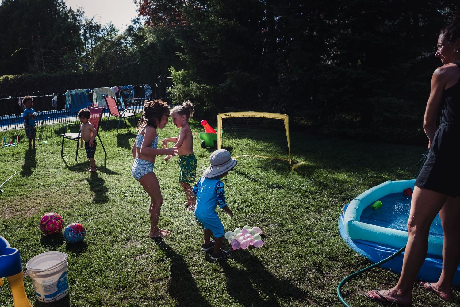 Colour image of children playing in the green grass at a family bbq.