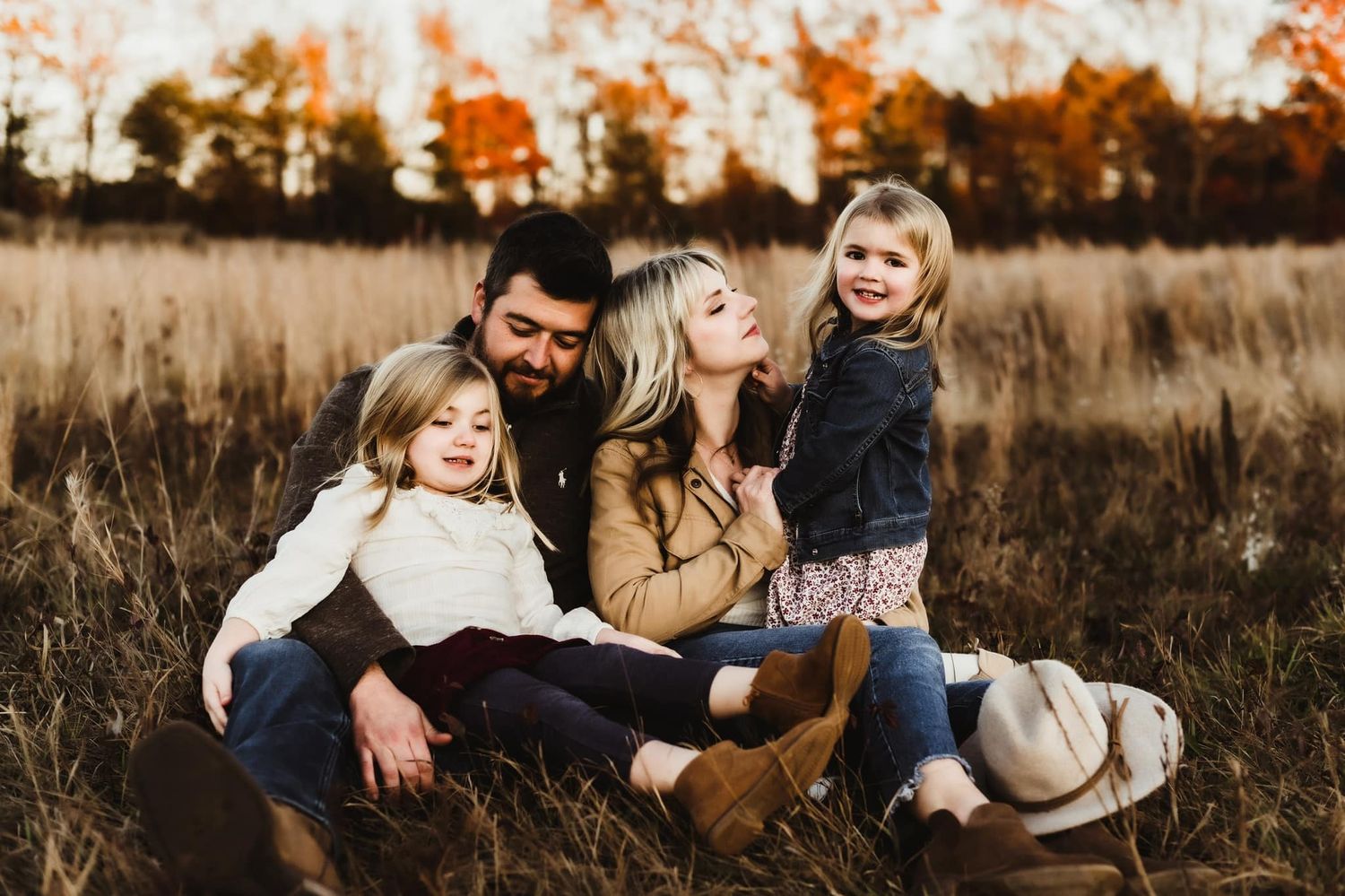 A joyful family moment captured in a golden autumn field at sunset.