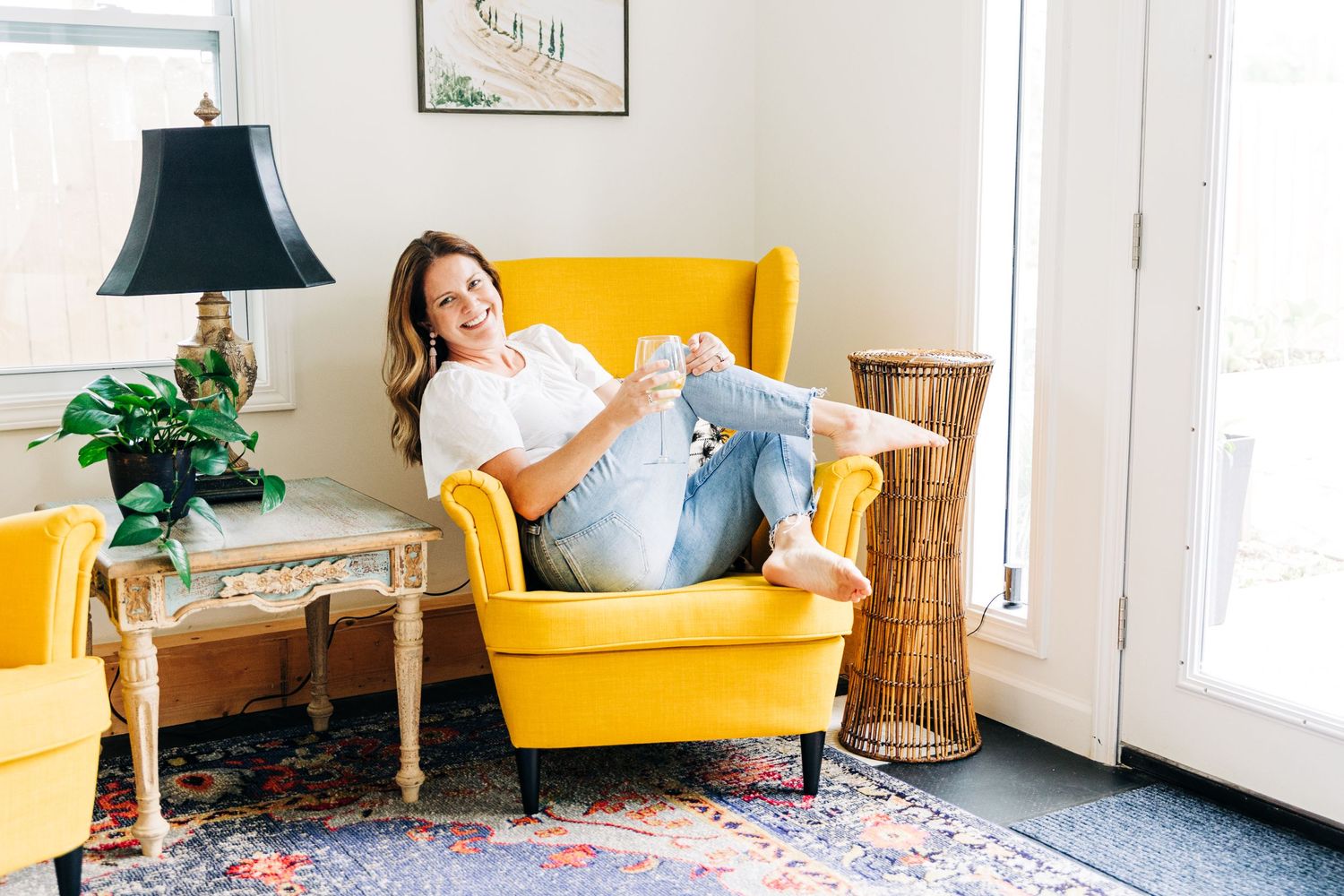 woman poses with coffee cup while sitting on a bright yellow couch at Little Villa Charlotte