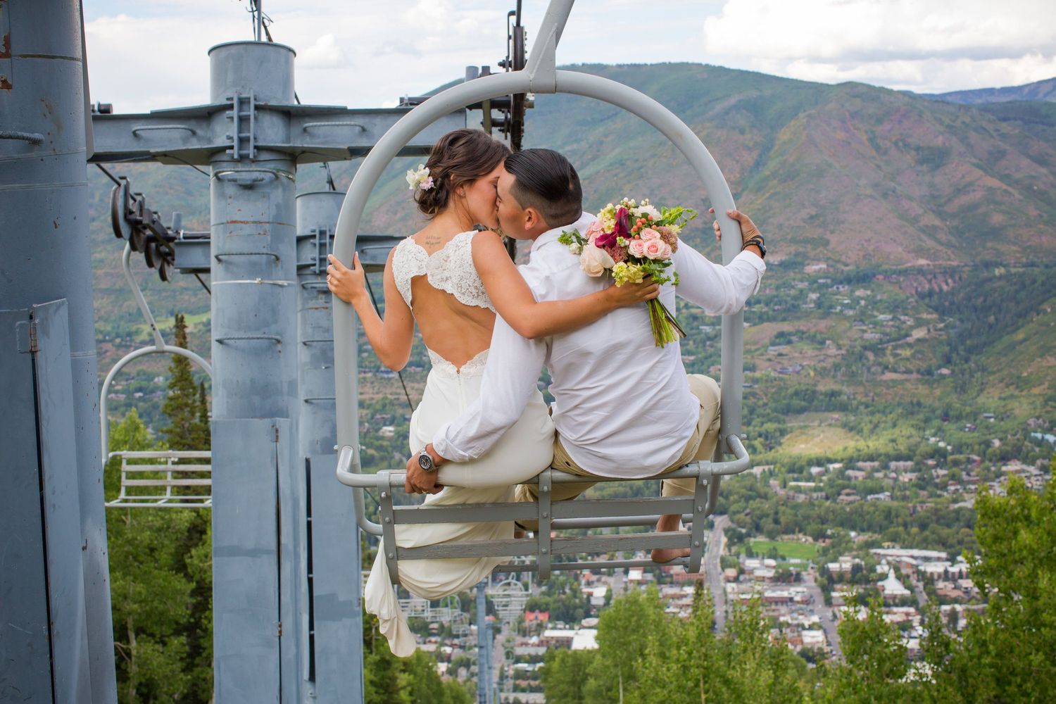 A couple sitting together on a chairlift with mountain valley views in the background.