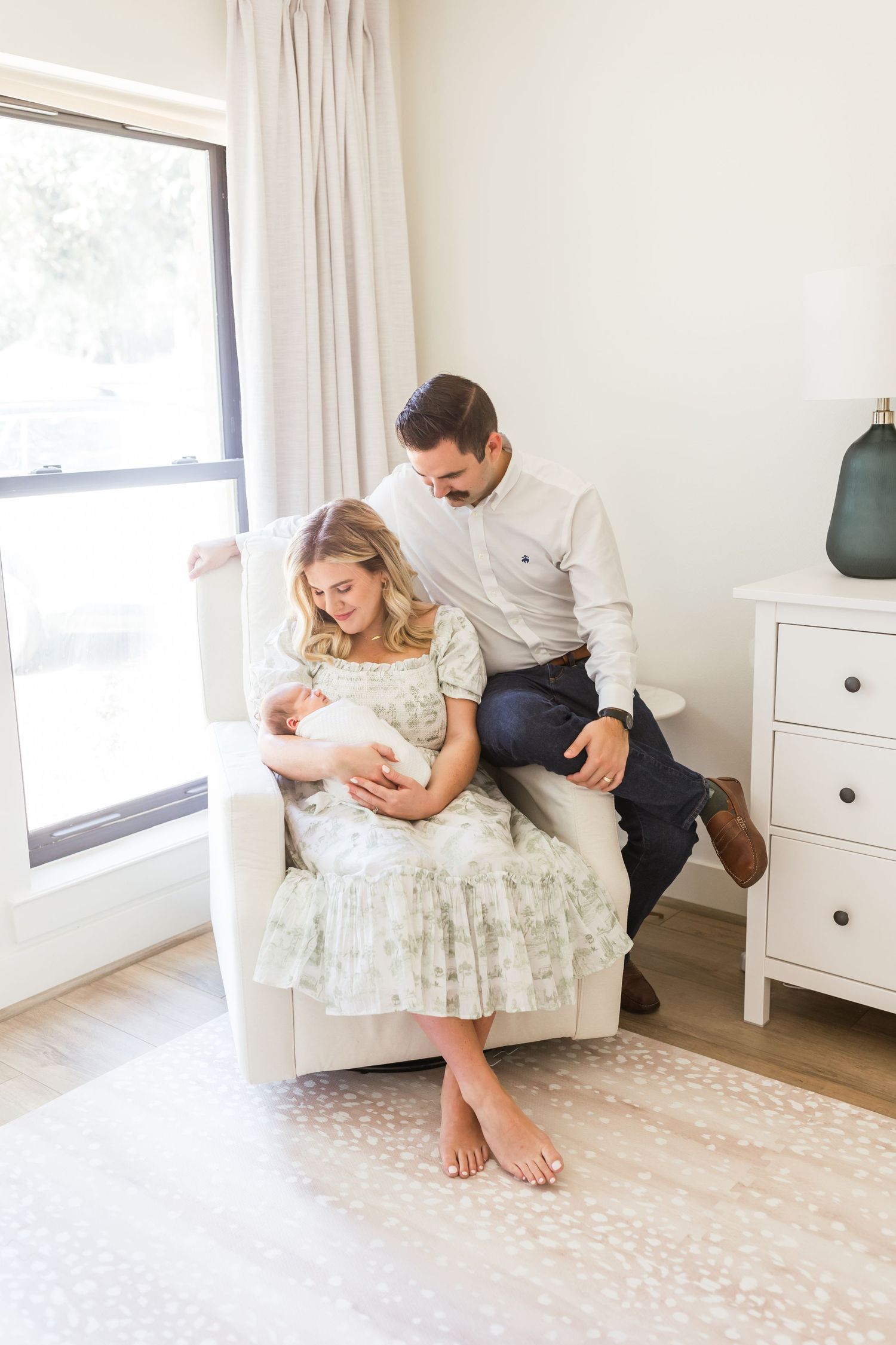 Parents sharing tender moment with newborn in bright nursery setting.