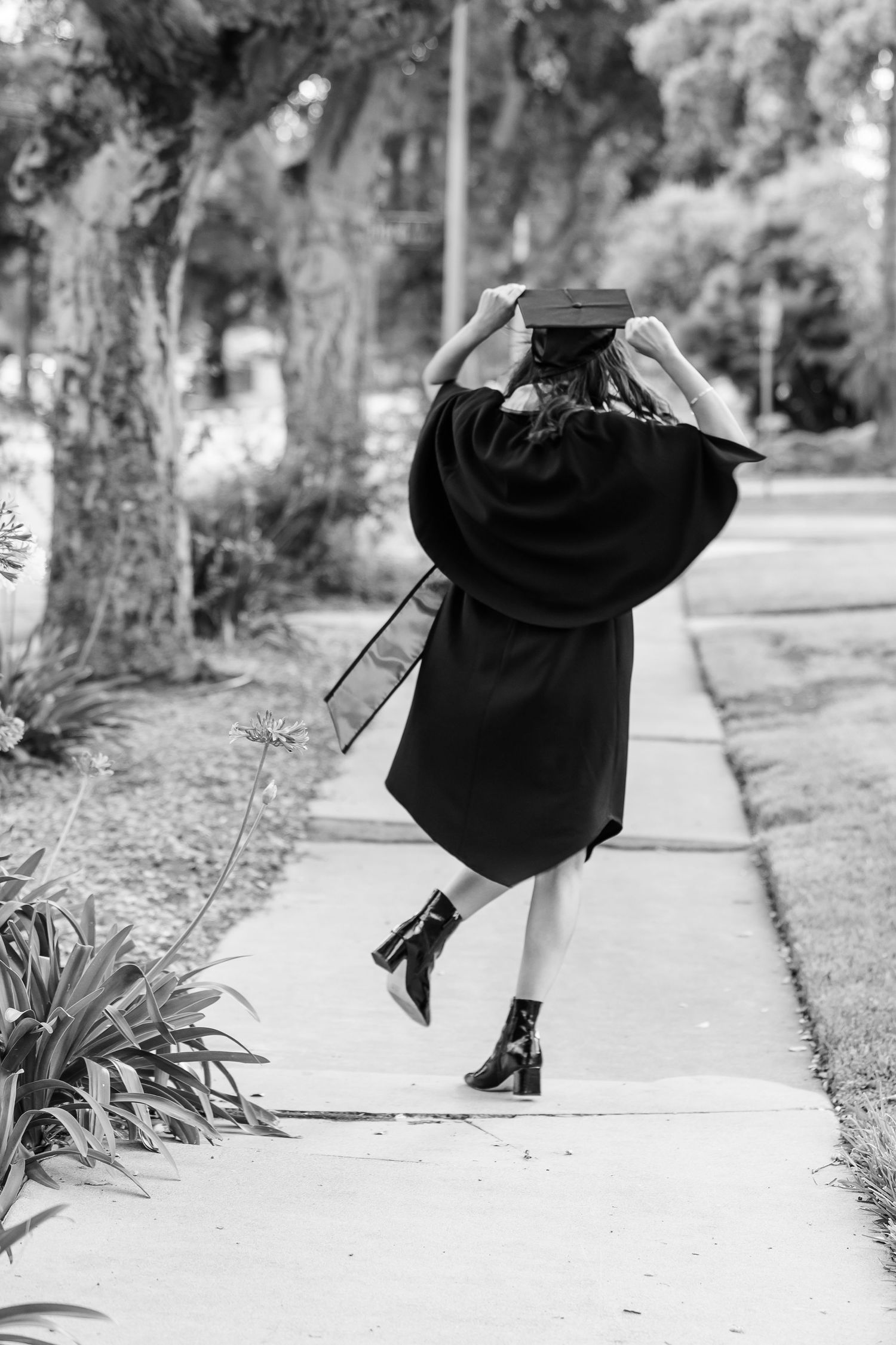 Girl jumping on the street in her cap and gown