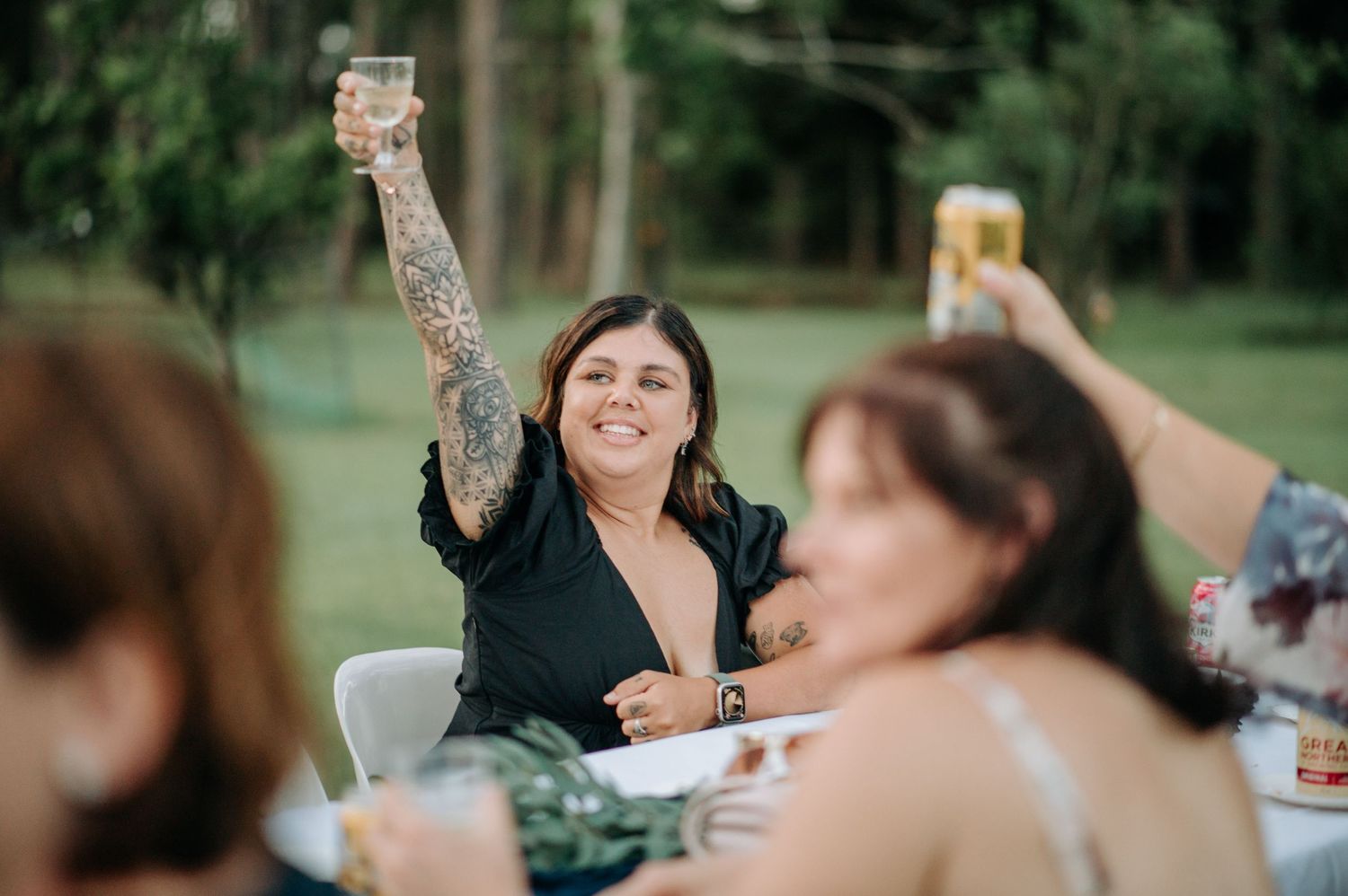 Wedding guest raising a glass in celebration during an outdoor reception.