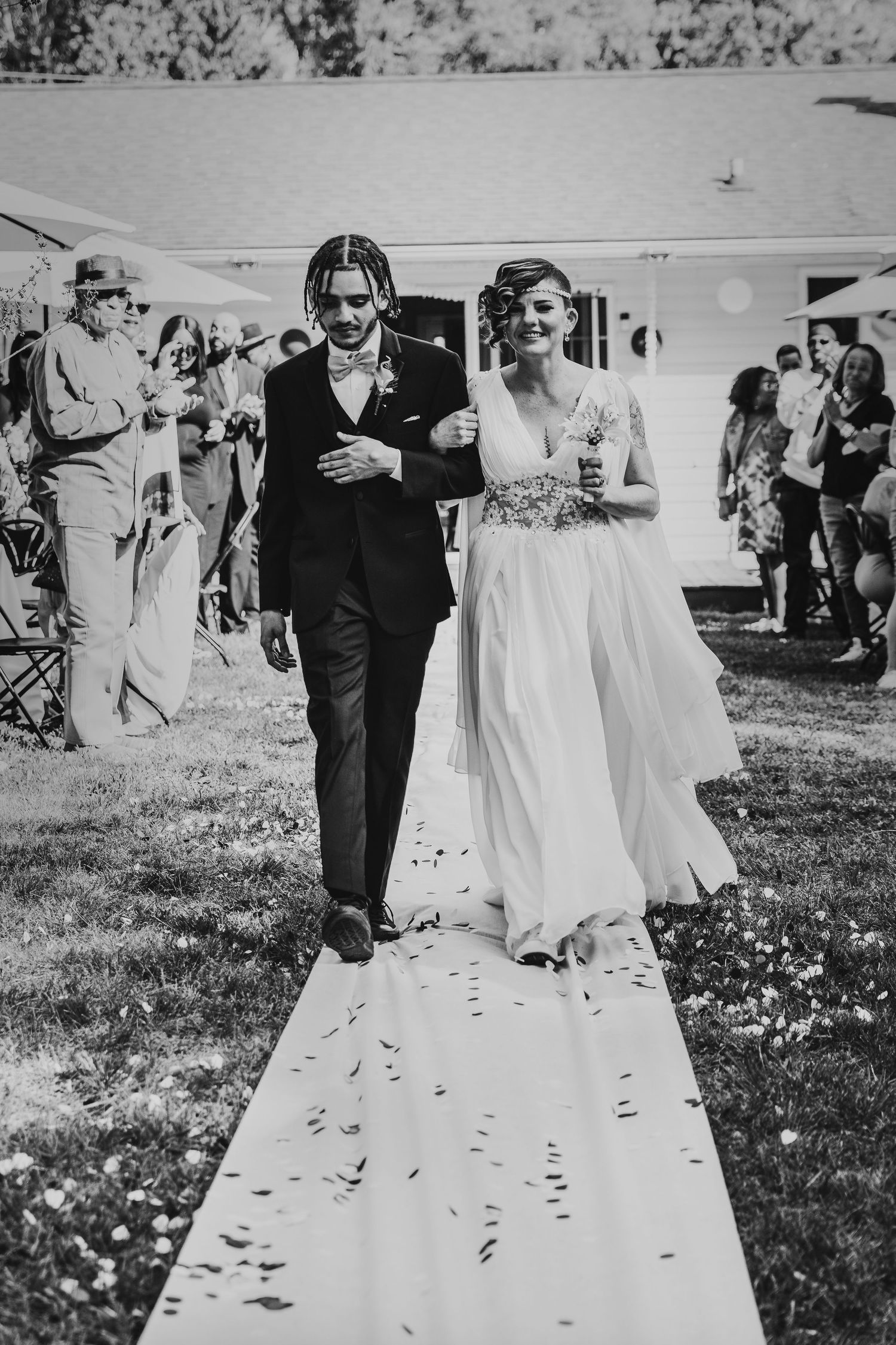 Black and white wedding photos showing couple walking on grass with scattered petals.