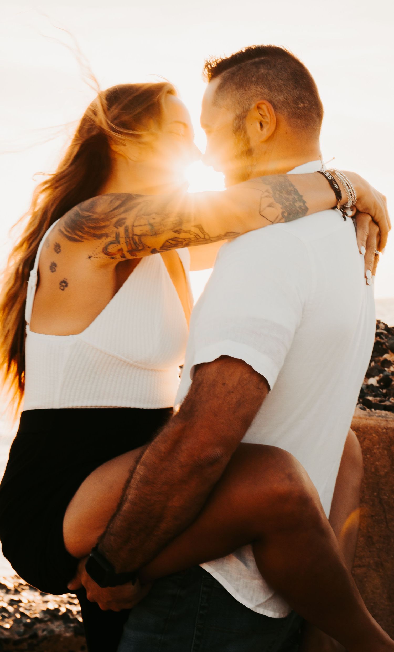Outdoor Engagement Session Ft. Desoto, St. Pete, FL; Couple embracing at sunset with sunflare