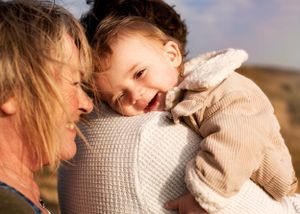 Photograph of a baby boy giggling over his dad's shoulder