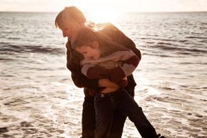 Fun sunset photoshoot of woman and daughter playing by the sea