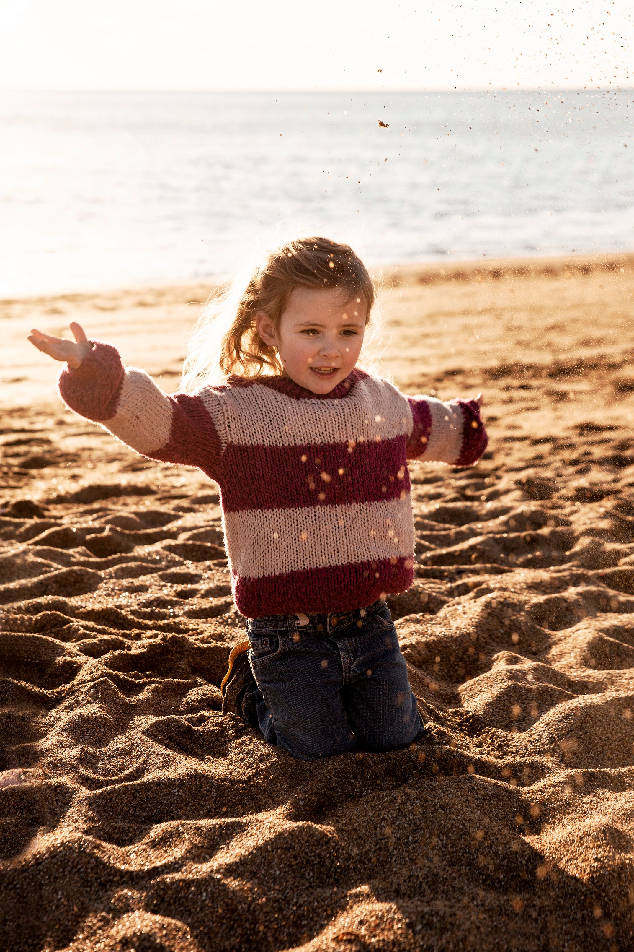 Toddler playing on the beach in golden sand at sunset