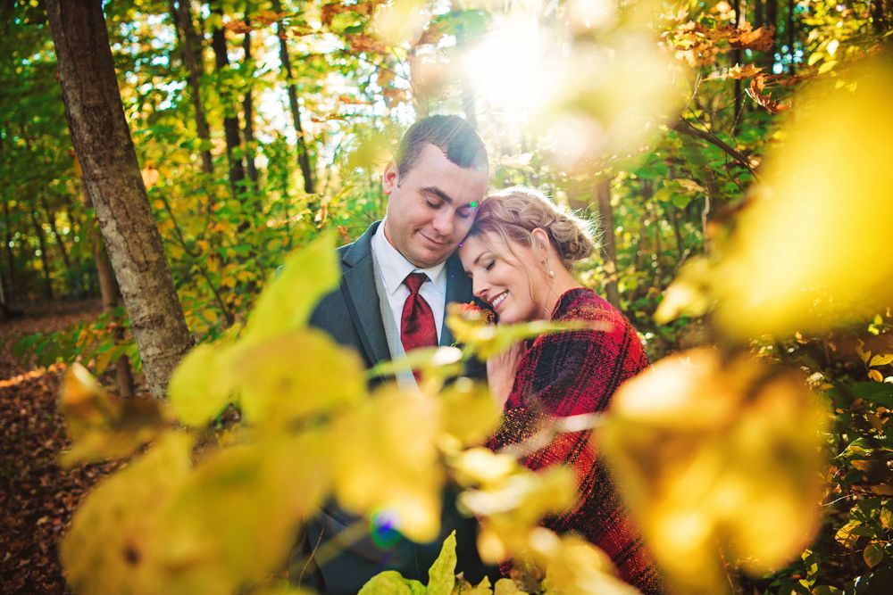 Wedding couple photographed through yellow autumn foliage in golden sunlight in Ilderton Area