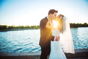 Wedding couple silhouetted against sunset over a lake with dramatic lighting in Windsor.