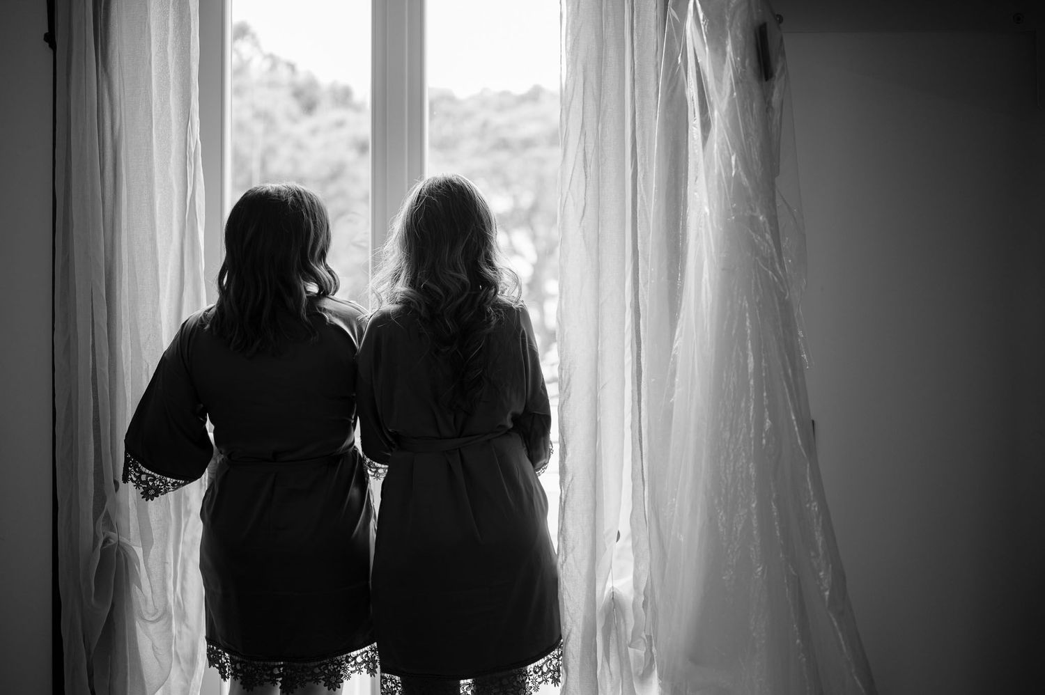 Silhouette of two women standing by window in matching robes.