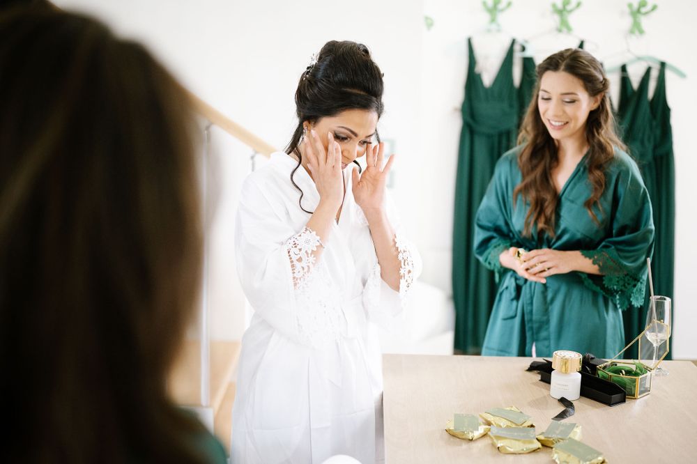 Candid moment of joy and laughter during pre-wedding preparations with teal robes visible.