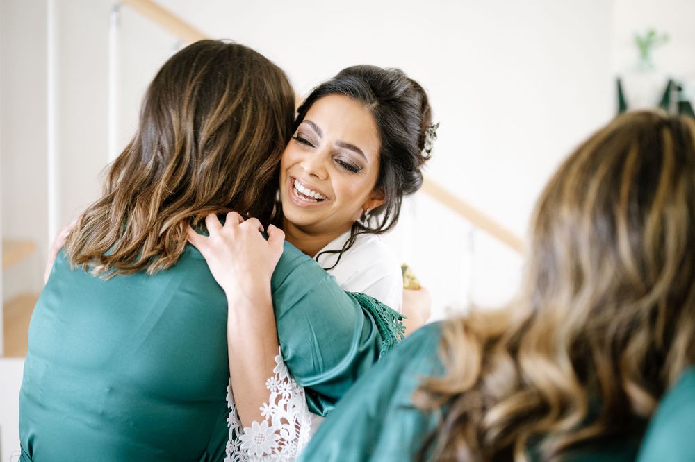 Emotional embrace shared between women in teal and white robes during pre-event preparations.