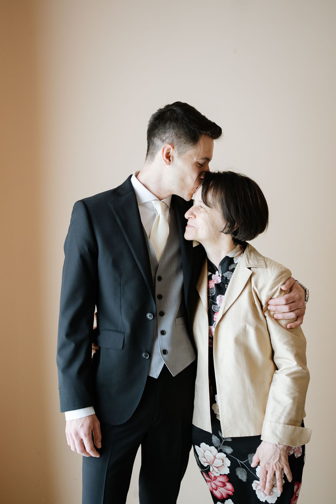 Intimate moment between groom in dark suit and guest in light blazer.