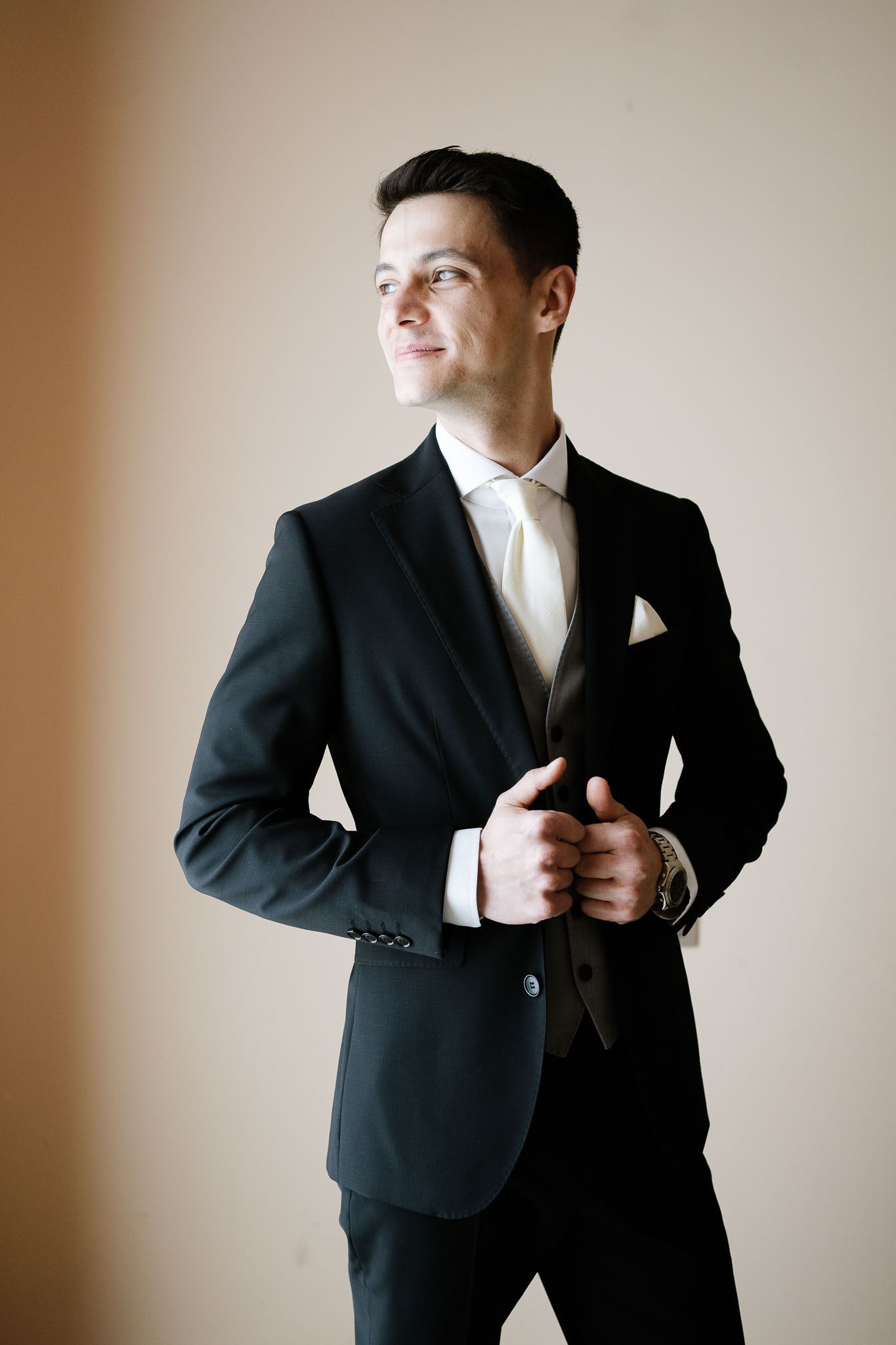 Classic black tuxedo with white tie on a groom standing against a neutral background.