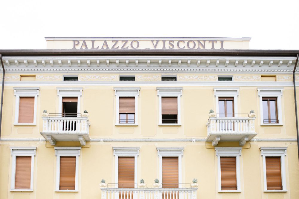 Yellow facade of Palazzo Visconti building with ornate balconies and classical architecture.