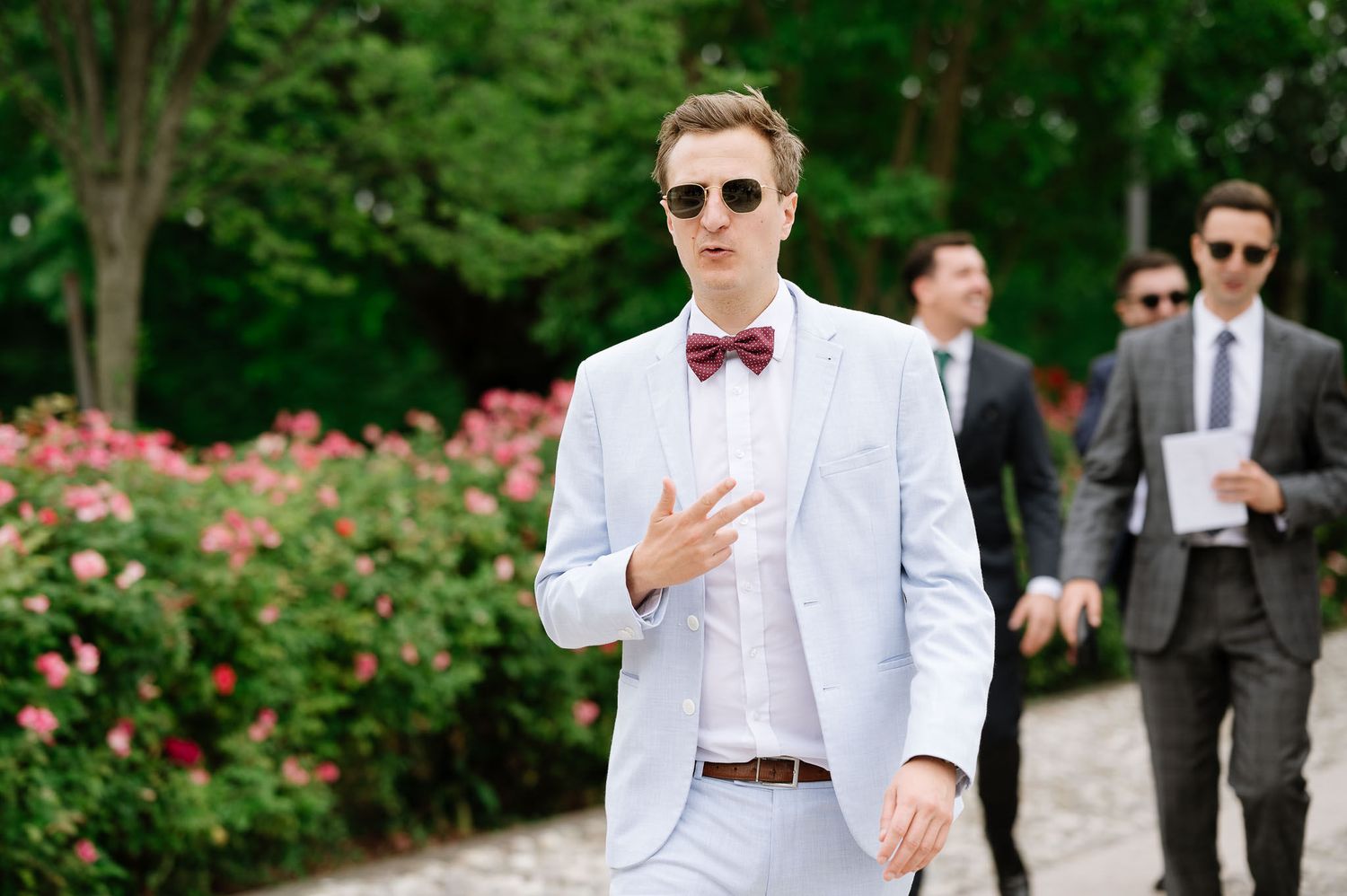 Stylish guest in light blue suit and bowtie at outdoor wedding celebration.