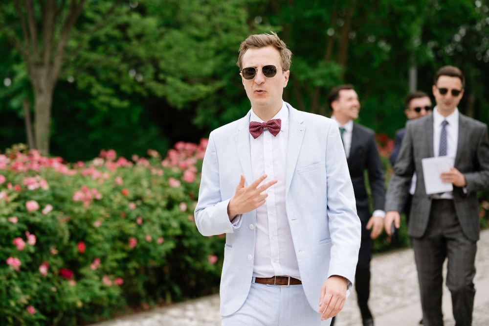 Stylish guest in light blue suit and bowtie at outdoor wedding celebration.