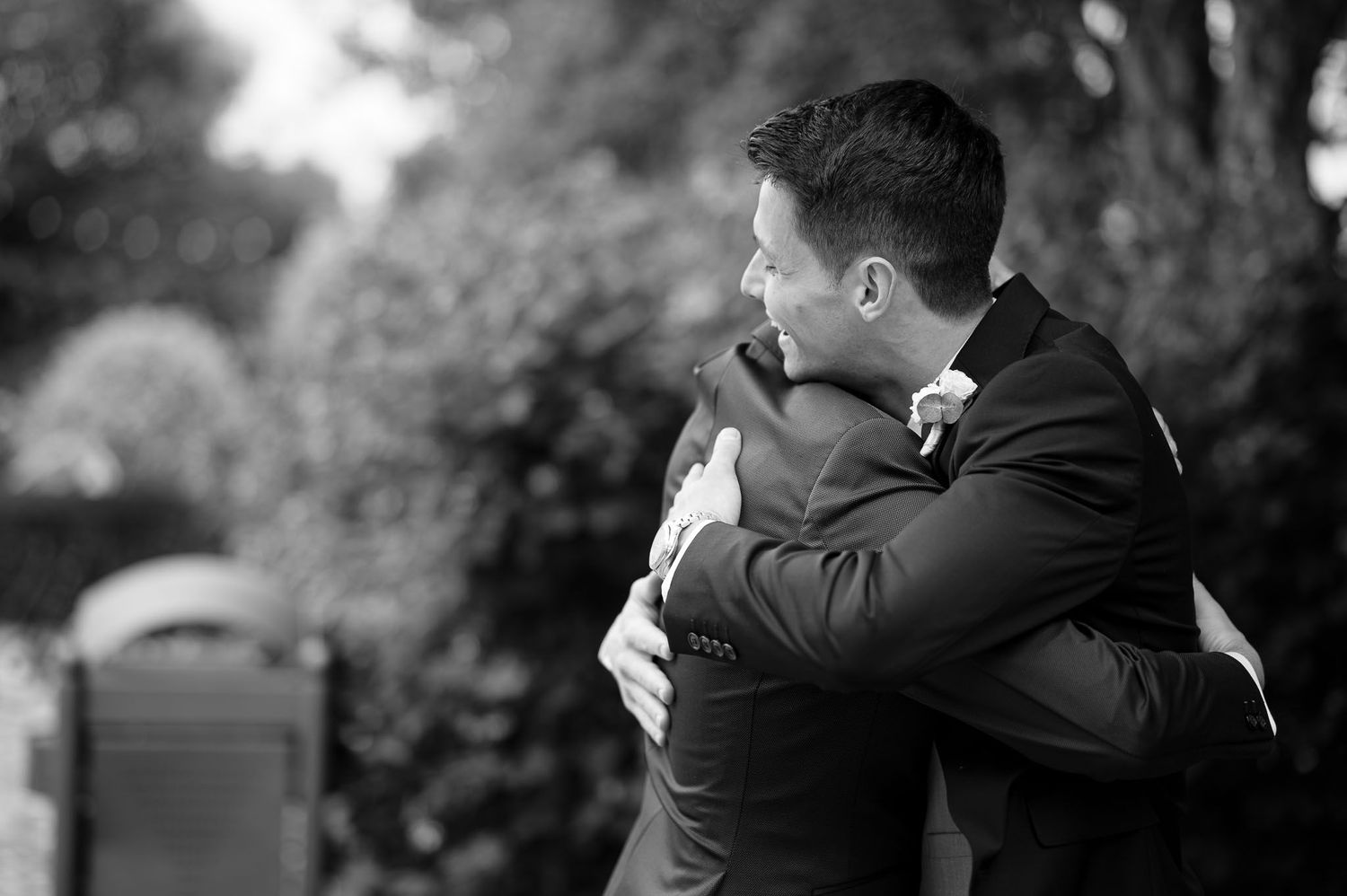 Emotional black and white photograph captures two people embracing at outdoor event.