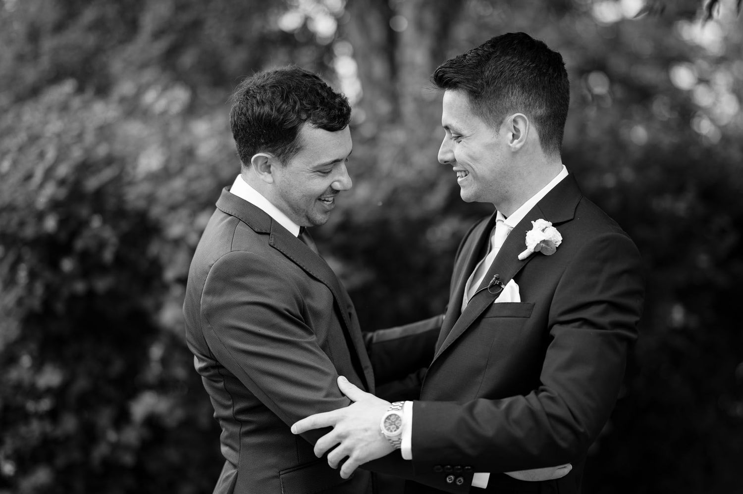 Intimate black and white moment between two people in formal attire at wedding celebration.