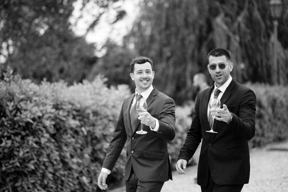 Two people in formal attire raise champagne glasses in black and white celebration photo.
