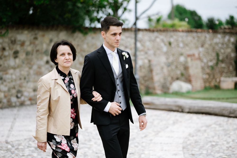 A couple walking arm in arm at a wedding venue with stone walls in the background.