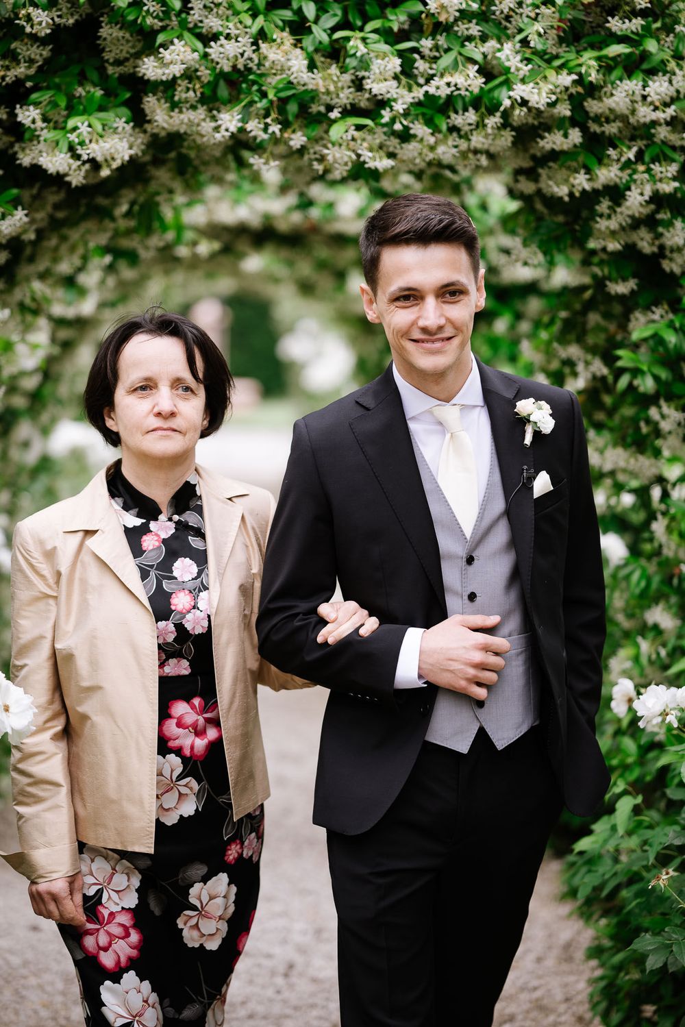 A couple poses together under flowering trees at an outdoor wedding venue.