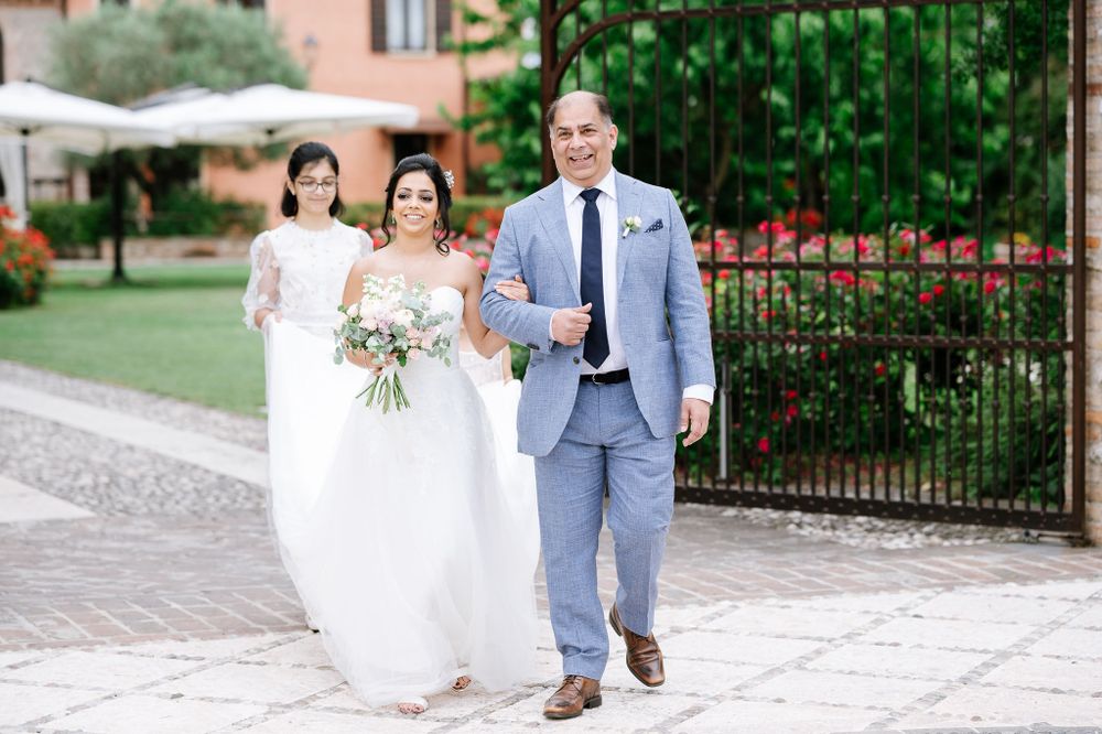 A bridal party walks along a stone path at an elegant Italian villa wedding venue.