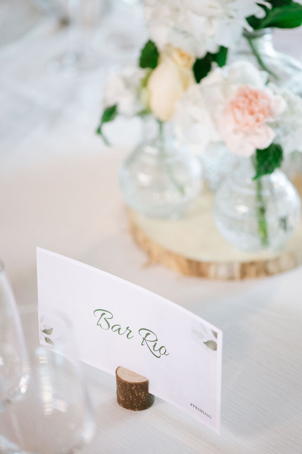Wedding place card reading 'Bar Rio' displayed with delicate floral centerpiece.