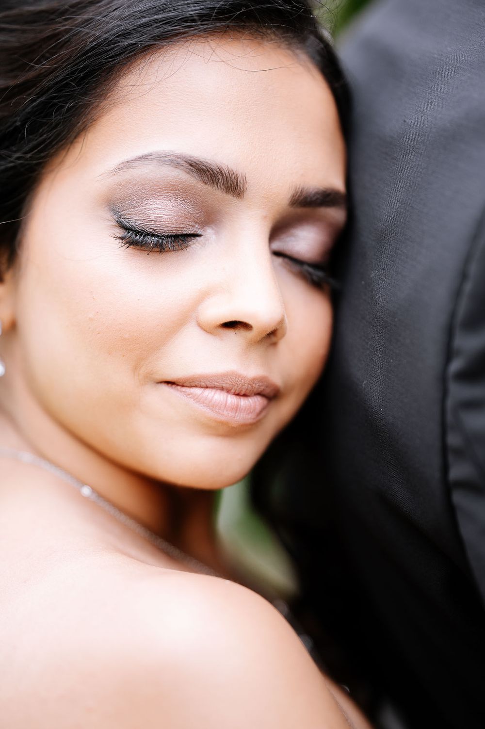 Close-up beauty shot showing delicate bridal makeup and jewelry.